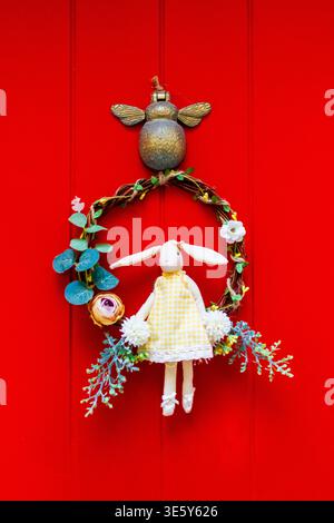Easter Bunny Wreath Decoration With Doll Hanging On Red Door For Spring Home Decor Stock Photo
