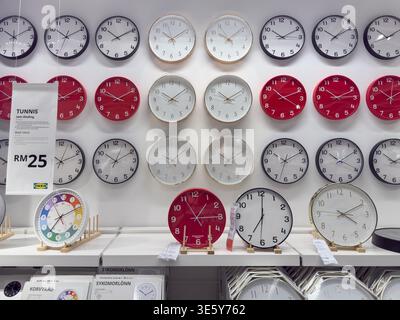 Penang, Malaysia - April 22, 2025: a selection of various wall clocks in different colors and designs hang on a white wall in an IKEA store. Prices ar Stock Photo