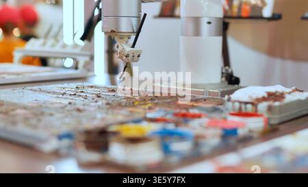Robot painting on palette, creating art at a technology exhibition Stock Photo