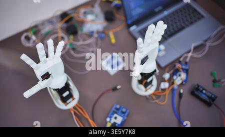 Robotic hands and electronic components on a workbench with a laptop Stock Photo