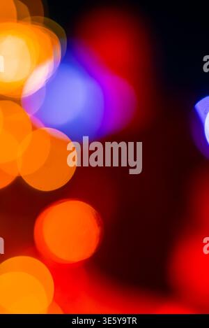 Out of focus bokeh circles in vivid tones on dark vertical frame Stock Photo