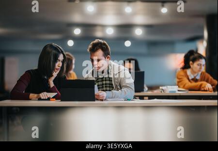 Tutor helping a young adult student with Down syndrome study on a tablet in a modern classroom Stock Photo