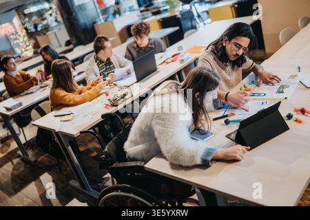 College students studying together in a modern classroom with peer tutoring and wheelchair access Stock Photo
