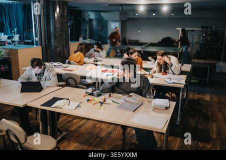 Students studying together in a modern shared study space with books and laptops Stock Photo
