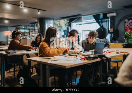 Diverse group of students collaborating on a study session around a table in a modern classroom Stock Photo