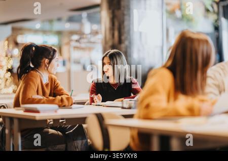 Students studying together in a modern classroom discussing notes during a group study session Stock Photo