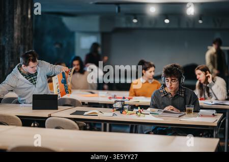 Students studying together in a shared classroom using books, tablets and headphones Stock Photo