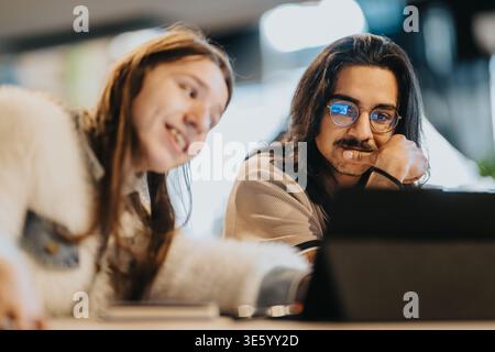 Two young people collaborating over a laptop in a casual study session Stock Photo