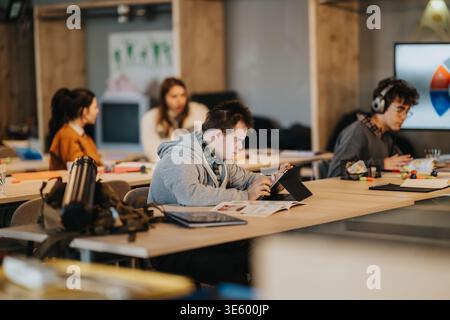 Young student with Down syndrome using a tablet in an inclusive classroom with peers studying together Stock Photo
