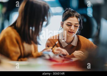 Two young women studying together and discussing notes in a cozy cafe or library setting Stock Photo