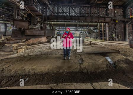 Tour guide Manuela Sass at the tapping point of Blast Furnace No. 5. It was the last and most modern blast furnace at the Thyssen steelworks in Meiderich. It came into operation in 1973 and produced special pig iron from ore at temperatures of up to 2,000 °C – as a feedstock for Thyssen’s steelworks. It was the last to be shut down on 4 April 1985, after only 12 years, due to crises in the steel market. Manuela Sass as a tour guide at Landschaftspark Duisburg-Nord (Duisburg-Nord Landscape Park). Duisburg, North Rhine-Westphalia, Germany Stock Photo
