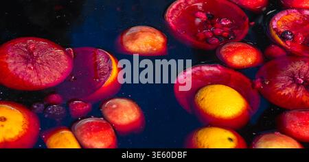 Colorful mix of citrus slices, strawberries and berries floating in dark liquid, creating vibrant abstract food composition suitable for beverage, det Stock Photo