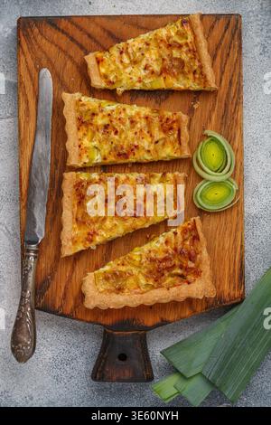 Freshly baked homemade onion pie stuffed with leeks, eggs and cheese on a wooden board. Tart. quiche. Homemade pastries for gourmets. Breakfast. Brunc Stock Photo