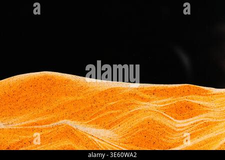 Golden sand horizon against deep black background. Minimalist landscape concept using layered sand art Stock Photo