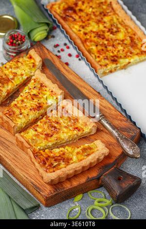 Freshly baked homemade onion pie stuffed with leeks, eggs and cheese on a wooden board. Tart. quiche. Homemade pastries for gourmets. Breakfast. Brunc Stock Photo