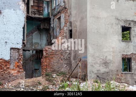 A heavily damaged derelict building with exposed brick, crumbling walls and broken windows stands amid rubble in Istanbul, Turkey Stock Photo