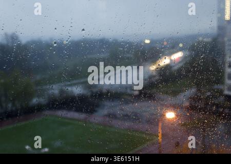 Rain drops on window with blurred city lights at dusk in Moscow Stock Photo