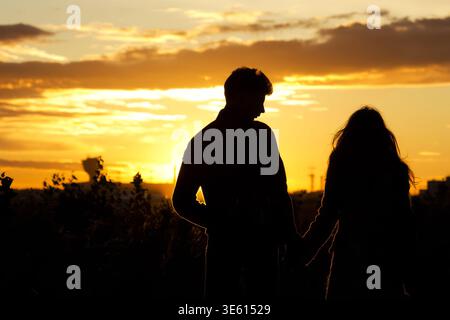 Silhouette of romantic couple holding hands at sunset Stock Photo