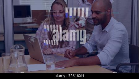 Reviewing team of three in business attire examining laptop at meeting table, with pitcher Stock Photo