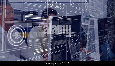 Working IT team analyzing code on monitors at adjacent desks in office, wearing shirts with HUD Stock Photo