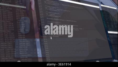 Displaying primary monitor showing code and terminal at desk, with keyboard, mouse reflection Stock Photo