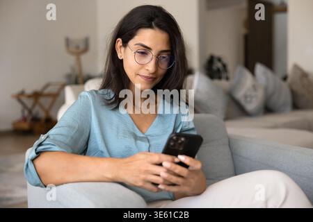 Young Brazilian woman in eyeglasses using smartphone Stock Photo