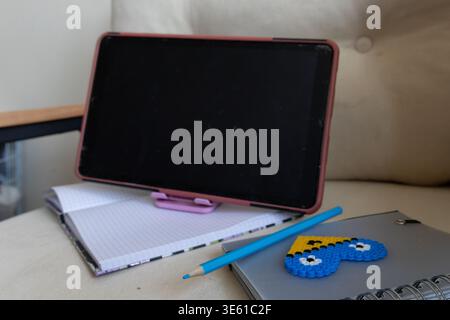 Online learning setup with tablet and study materials on cozy chair in home environment Stock Photo