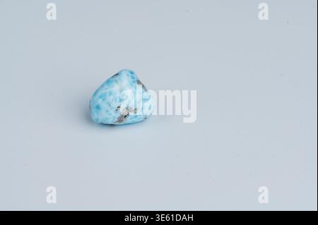 A blue and white Larimar gemstone sits on a flat, light surface. Stock Photo