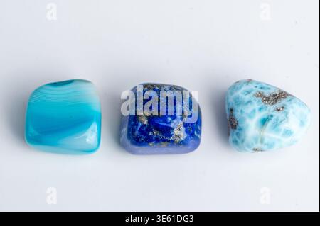 Three stones of different colors sit on a white surface under light. Stock Photo