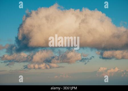 Calm Atmospheric Scene Showcasing Large Cloud Formations Illuminated By Soft Golden Sunlight Near Horizon Stock Photo