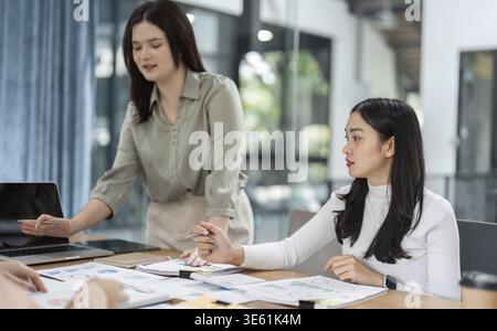 A group of diverse office workers engages in a collaborative meeting, analyzing financial charts and strategies Stock Photo