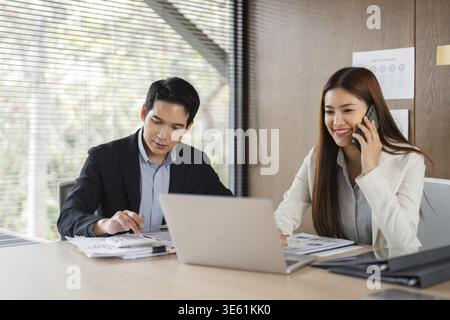A focused atmosphere as a man and woman collaborate over documents and a laptop, analyzing data and discussing business strategies in a bright office Stock Photo