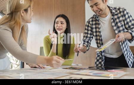A diverse group of professionals sharing ideas and collaborating on a design project while engaged in discussion around an office table Stock Photo
