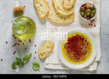 Freshly baked homemade ciabatta and a sauce of olive oil and balsamic vinegar, freshly ground pink pepper, coarse sea salt and basil on a light backgr Stock Photo