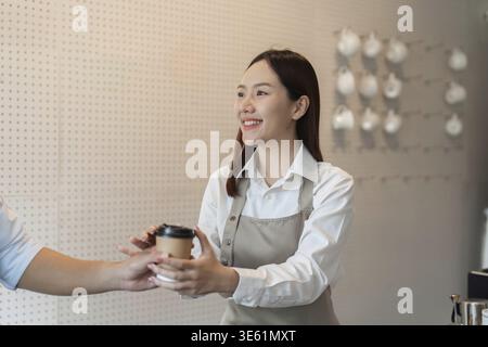 A barista shares an eco-friendly reusable cup as part of the coffee exchange process, promoting a sustainable lifestyle and customer engagement in was Stock Photo