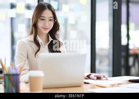 A businesswoman is focused on analyzing data and managing online investments. Her professional work includes finance, accounting, and decision-making. Stock Photo