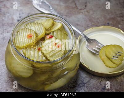 Scheiben eingelegter Gurken mit Pfeffer und Senf im Glas. Snack fuer Feinschmecker. Selektiver Fokus Stock Photo