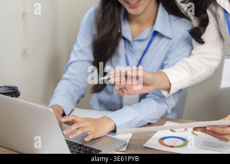 Two women collaborating over financial data on a laptop, highlighting teamwork and professional engagement in a modern workspace Stock Photo