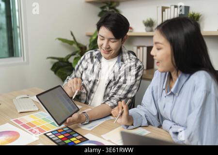 Two designers discuss and showcase their UX and UI design ideas on a tablet, enhancing their collaborative effort Stock Photo