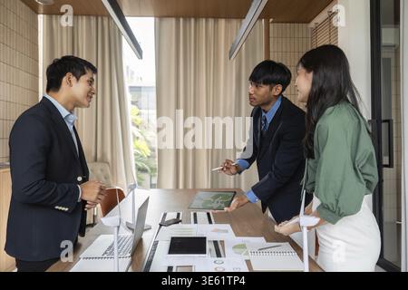 A diverse team of professionals engaged in a sustainability meeting, discussing ESG solutions with enthusiasm and collaboration in a modern office Stock Photo