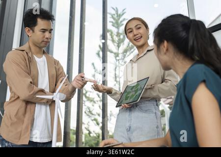 A diverse team collaborates on sustainable business practices, showcasing ESG initiatives with charts and models in a contemporary workspace Stock Photo