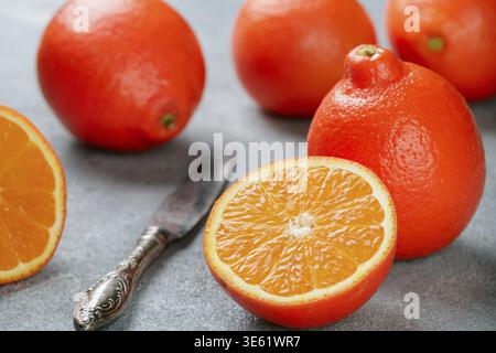 Mineola. Tangerine. Juicy sweet orange citrus fruit whole and sliced on a concrete background. Selective focus Stock Photo