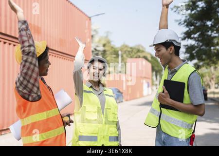 Three construction professionals, including a female supervisor and two male workers, celebrate their success with high-fives while collaborating on p Stock Photo