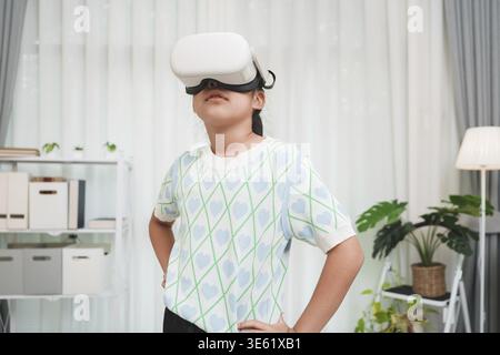 Child student using VR headset in a home learning environment. Concept of immersive education, gaming, and digital technology for kids Stock Photo