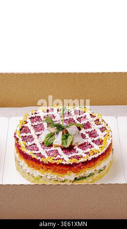 Food, A vibrant layered salad featuring colorful vegetables, fish, and cream sits in a cardboard box. This dish showcases an array of textures and fla Stock Photo