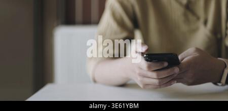 Mockup image of a woman holding mobile phone with blank black screen in cafe Stock Photo