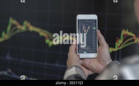 Business man trader investor analyst using mobile phone app analytics for cryptocurrency financial stock market analysis analyze graph trading data in Stock Photo
