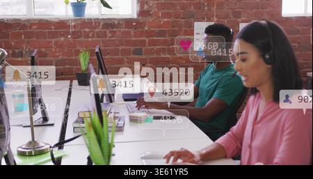 Typing woman in pink blouse, headset at right desk with monitor and notification icons, copy space Stock Photo