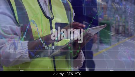 Using tablet, lead wearing hi-vis vest and lanyard tapping screen at plant line, with stock overlay Stock Photo