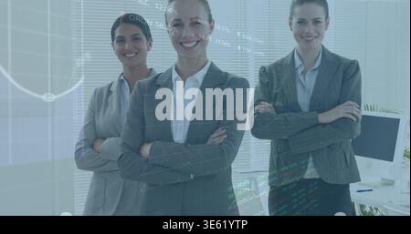 Standing three businesswomen wearing blazers in office with monitor, plant and stock chart overlay Stock Photo